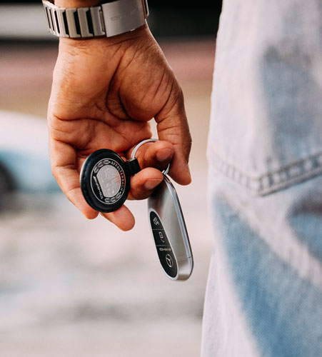 Zu sehen ist ein Mercedes AMG Schlüsselanhänger, der an einem Autoschlüssel befestigt ist und von einer Person in der Hand gehalten wird.