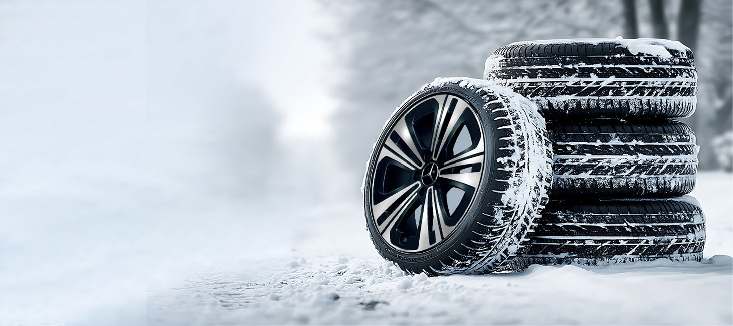 Mercedes-Benz Winterkompletträder Abgebildet wird ein Radsatz Winterkompletträder von Mercedes-Benz. Ein Rad wurde neben den Stapel gestellt, zur Felgendarstellung. Die Räder stehen auf einer beschneiten Straße.