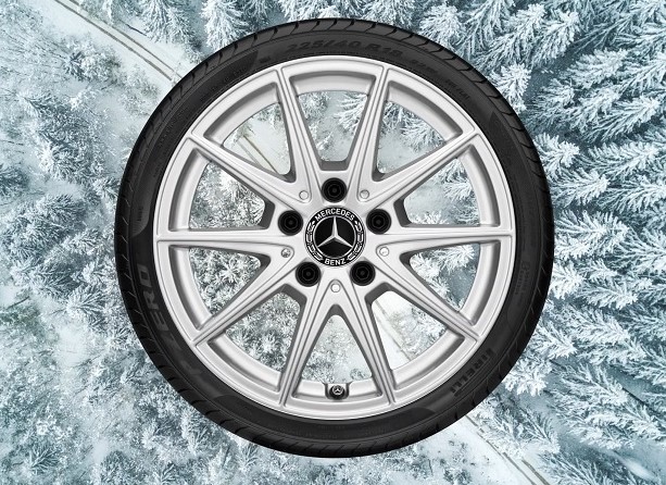 Ein Rad mit silberner Felge vor dem Hintergrund eines beschneiten Waldes. Verlinkt auf die Kategorie: Kompletträder