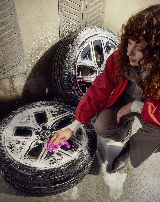 Mercedes-Benz Pflegemittel Zu sehen ist eine junge Frau, die mit Mercedes-Benz Pflegemitteln zwei Kompletträder reinigt.